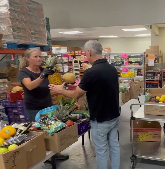 Volunteers packing fresh produce onto a cart at a pantry station